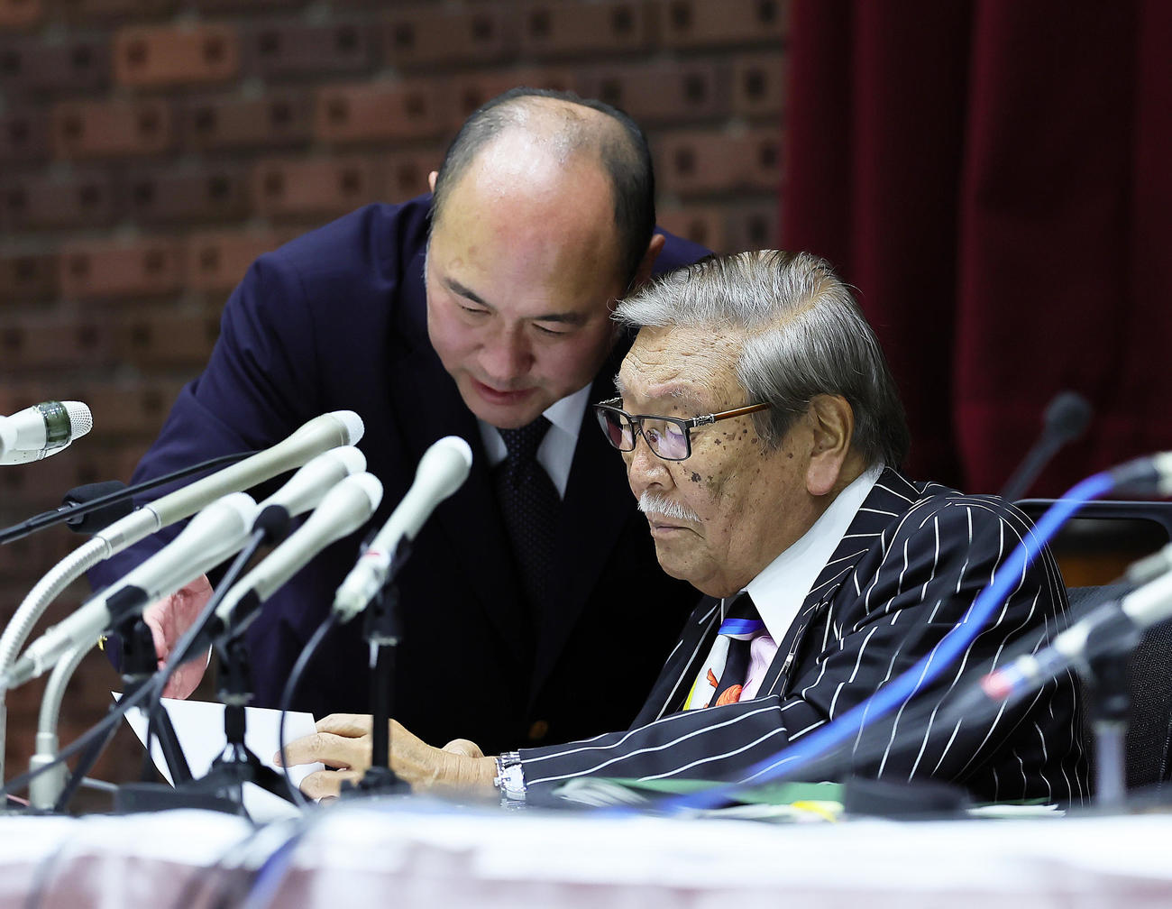 会見中、司会者（左）と話す第三者委員会の久保利英明議長（撮影・足立雅史）
