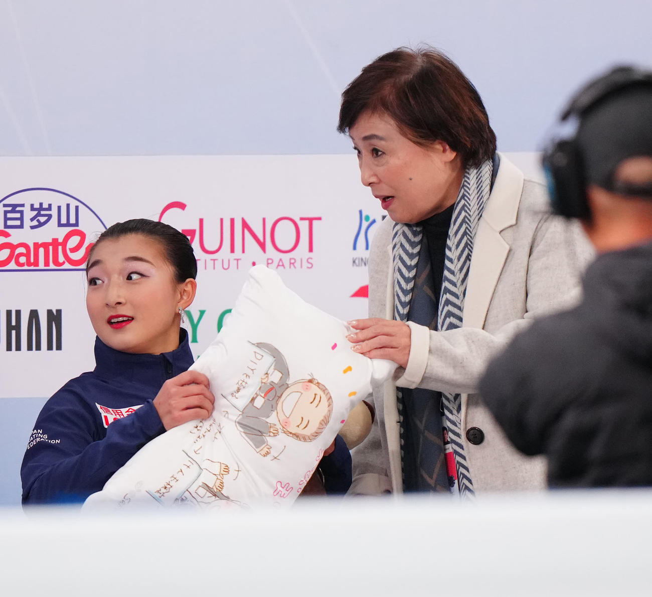 女子SPの演技後、キス・アンド・クライでクッションを手にする坂本（左）。右は中野コーチ
