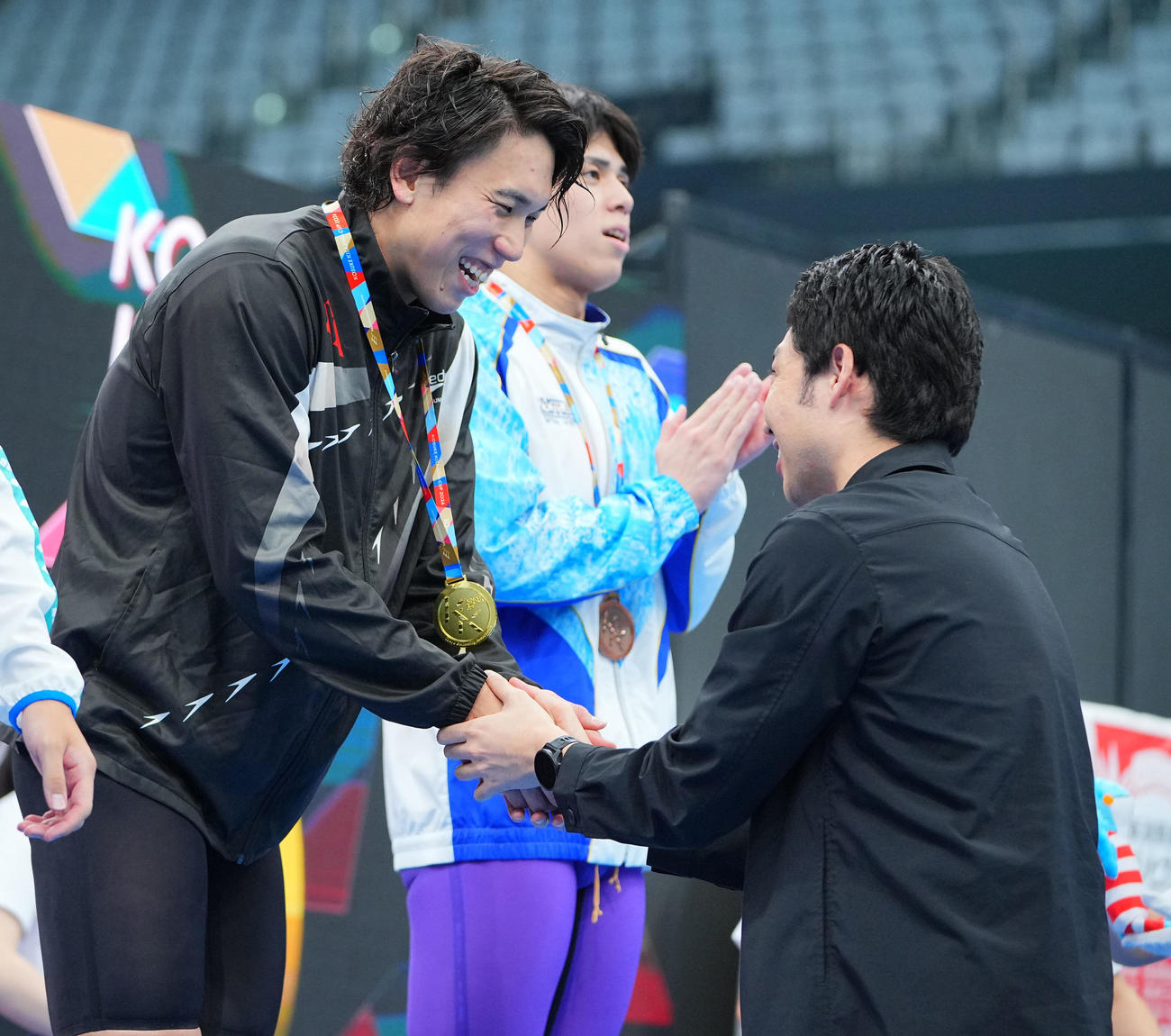男子200メートル自由形で優勝した松元（左）は萩野氏からメダルを渡され笑顔を見せる（撮影・垰建太）