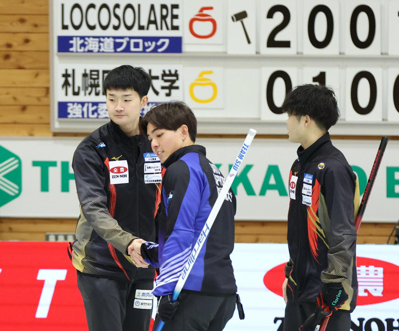ロコ・ソラーレ対札幌国際大学　札幌国際大学に勝利し握手をするロコ・ソラーレの前田拓（左後方）（撮影・佐藤翔太）