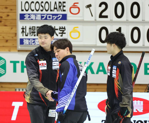 ロコ・ソラーレ対札幌国際大学　札幌国際大学に勝利し握手をするロコ・ソラーレの前田拓（左後方）（撮影・佐藤翔太）