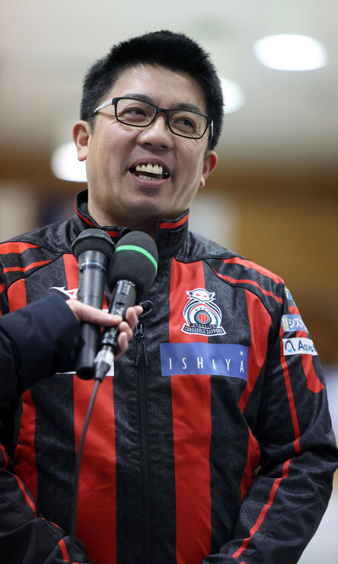 SC軽井沢クラブ対コンサドーレ　優勝し笑顔でインタビューに応じるコンサドーレの敦賀信コーチ（撮影・佐藤翔太）