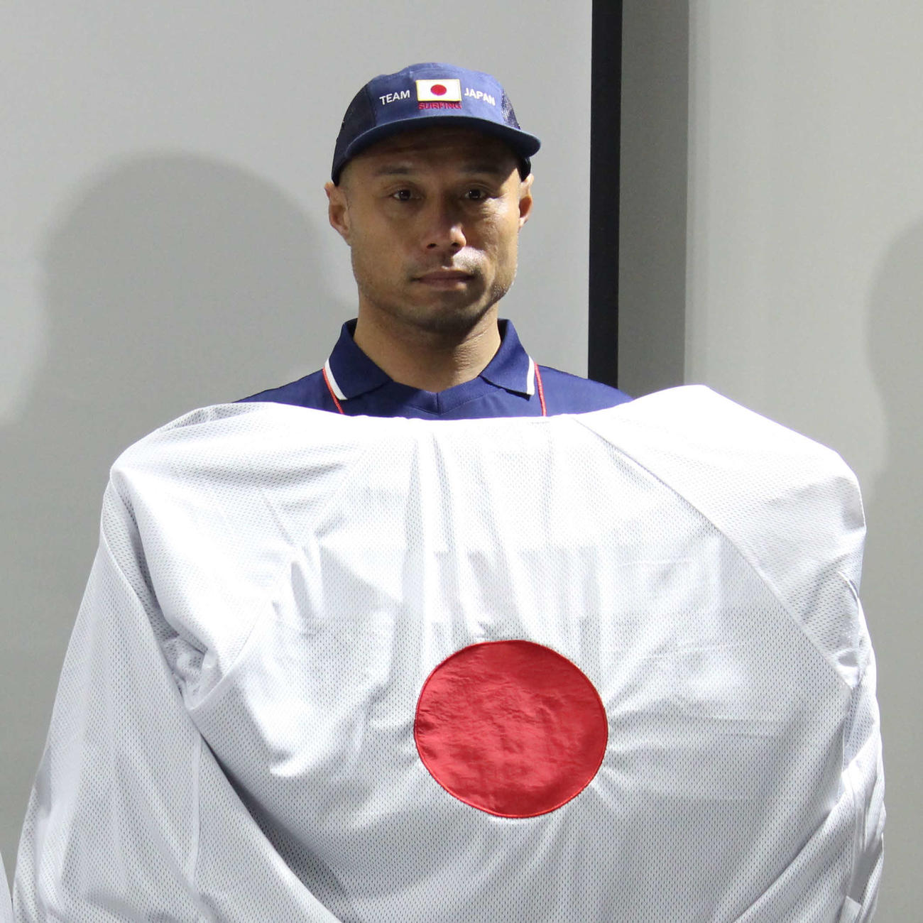 代表の新ユニホームを掲げる大野コーチ（撮影・勝部晃多）