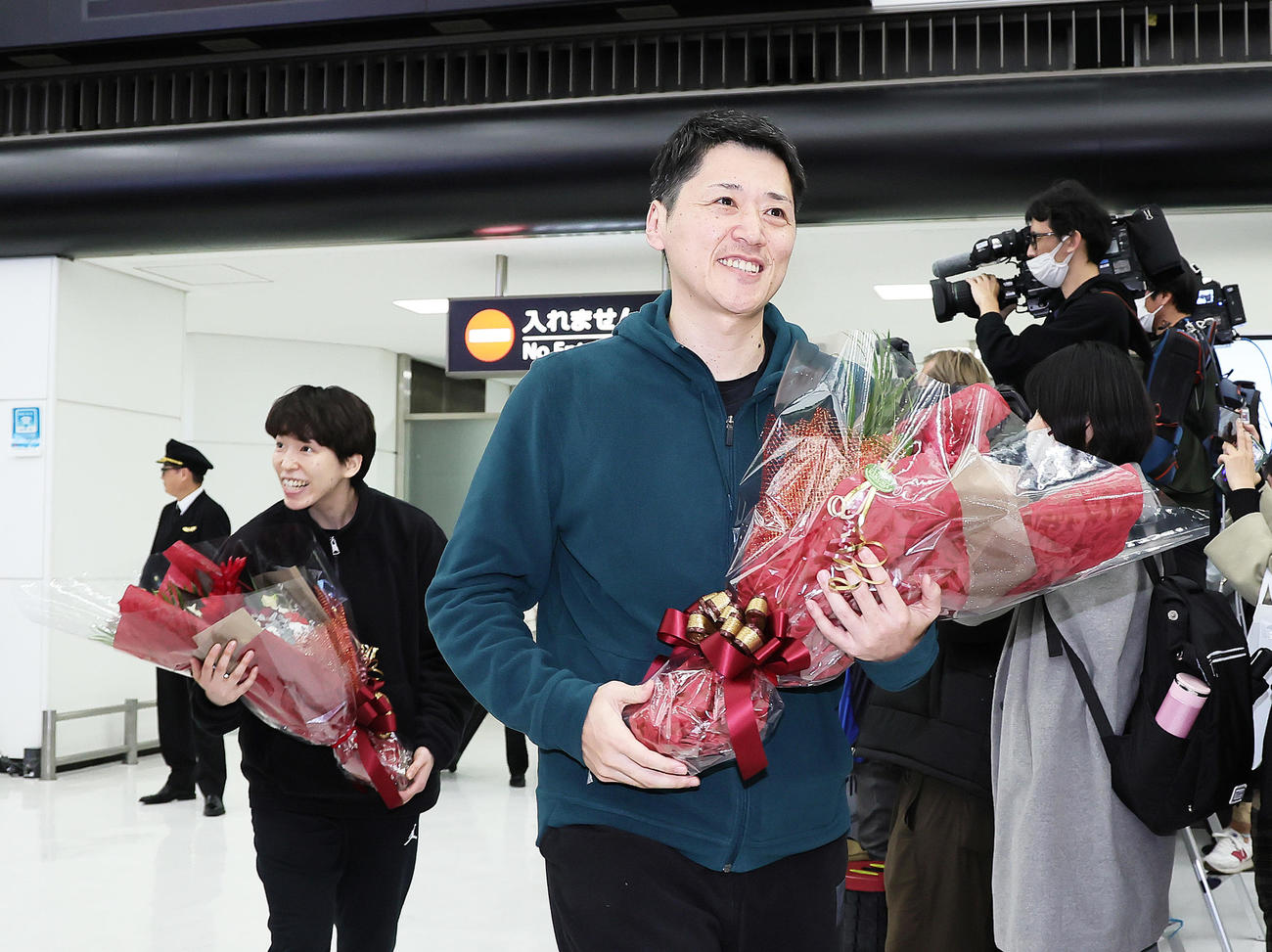 帰国し、花束を手に笑顔のバスケットボール女子日本代表の林主将（左）と恩塚監督（撮影・足立雅史）