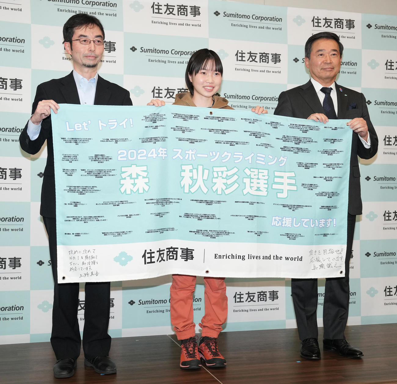 激励会で横断幕を手に記念撮影する森秋彩（中央）と住友商事の兵頭誠之代表取締役（右）