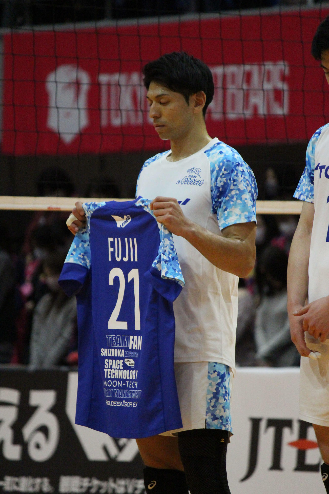 藤井直伸さんのユニホームを掲げ、黙とうをささげる東レの峯村主将（撮影・勝部晃多）