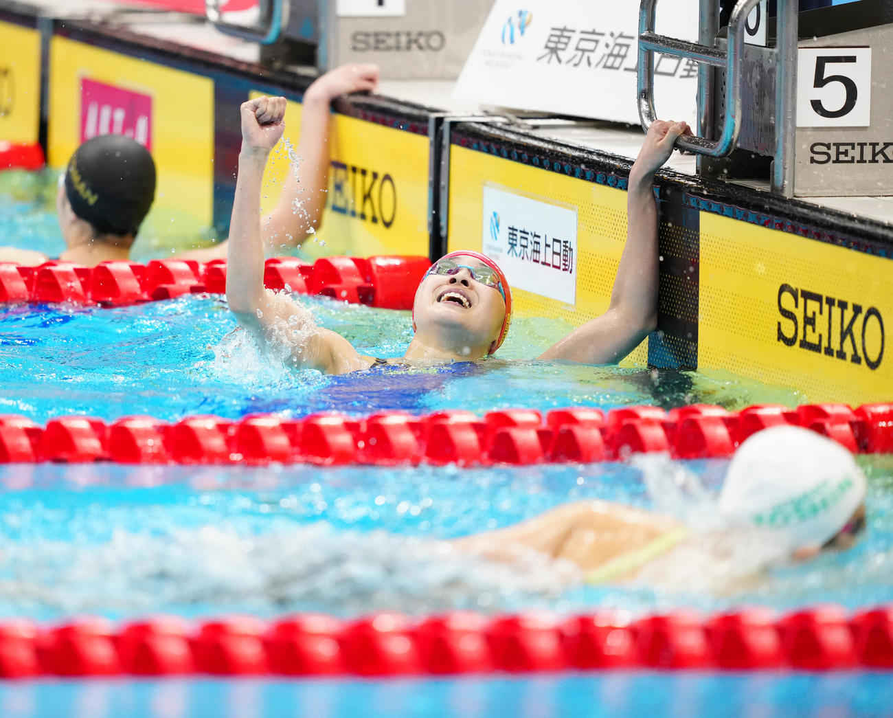 パリ五輪代表選考会の女子400メートル個人メドレー決勝で派遣標準記録に届き、ガッツポーズの成田（中央）（撮影・江口和貴）