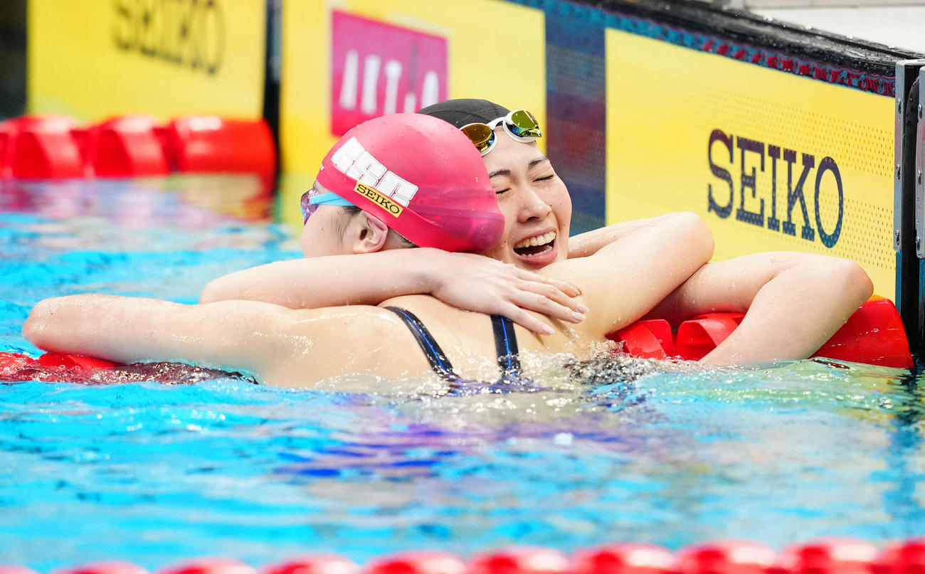 パリ五輪代表選考会の女子400メートル個人メドレー決勝で派遣標準記録に届き、成田（手前）と抱き合う谷川（撮影・江口和貴）