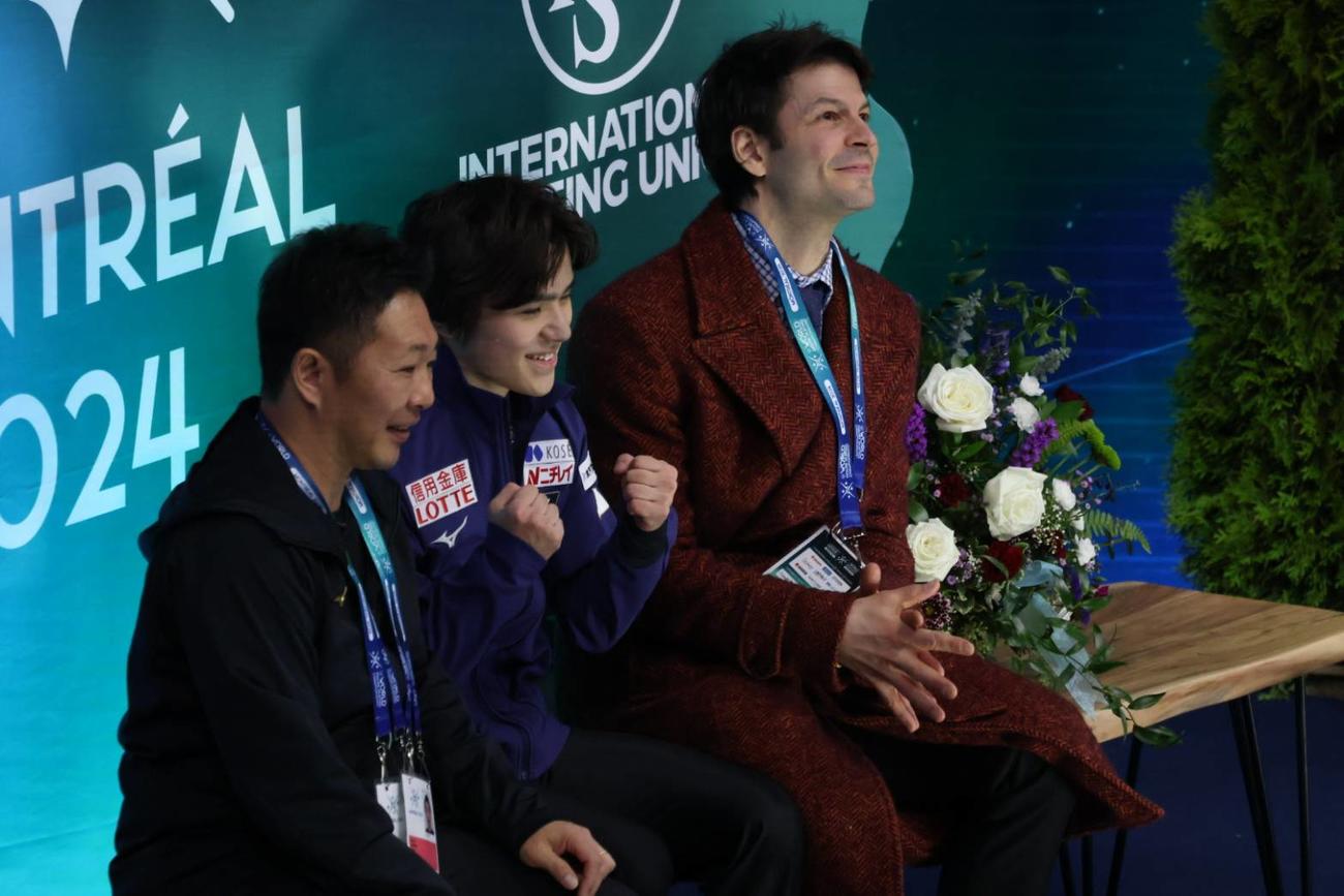世界選手権SPを終えてガッツポーズを見せる宇野昌磨（中央）。右はステファン・ランビエル・コーチ、左は出水慎一トレーナー
