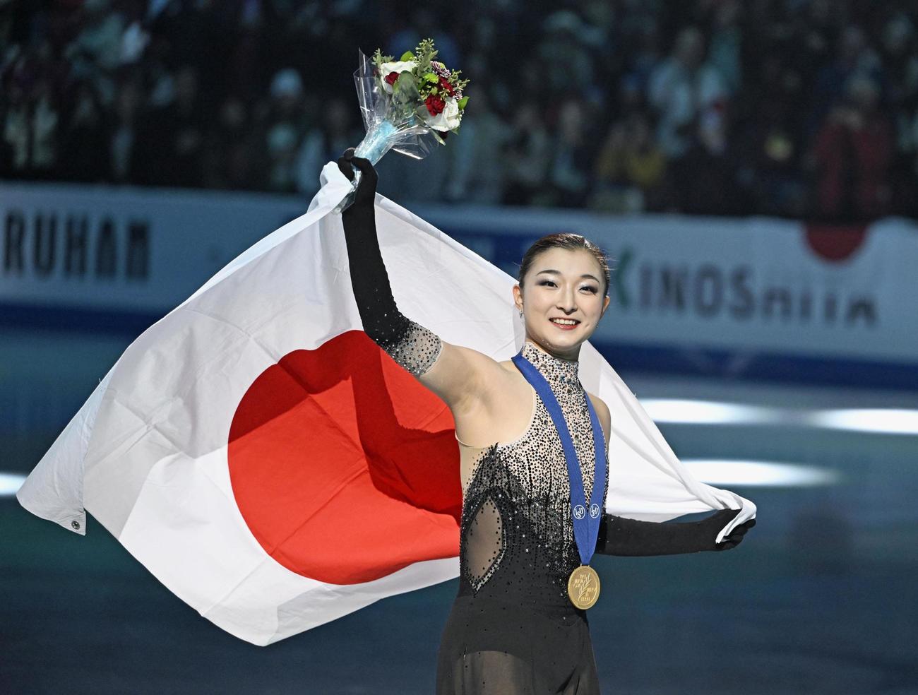 フィギュアスケート世界選手権の女子で56年ぶりとなる3連覇を果たし、日の丸を掲げる坂本花織（共同）