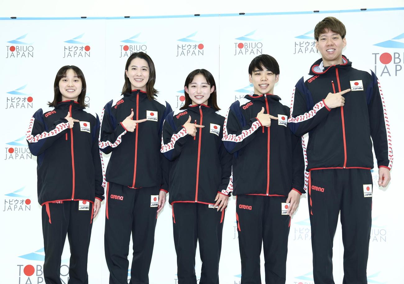 日の丸を指差し笑顔で写真に納まるパリ五輪競泳代表選手たち。左から成田、大橋、三井、寺門、渡辺（撮影・河田真司）
