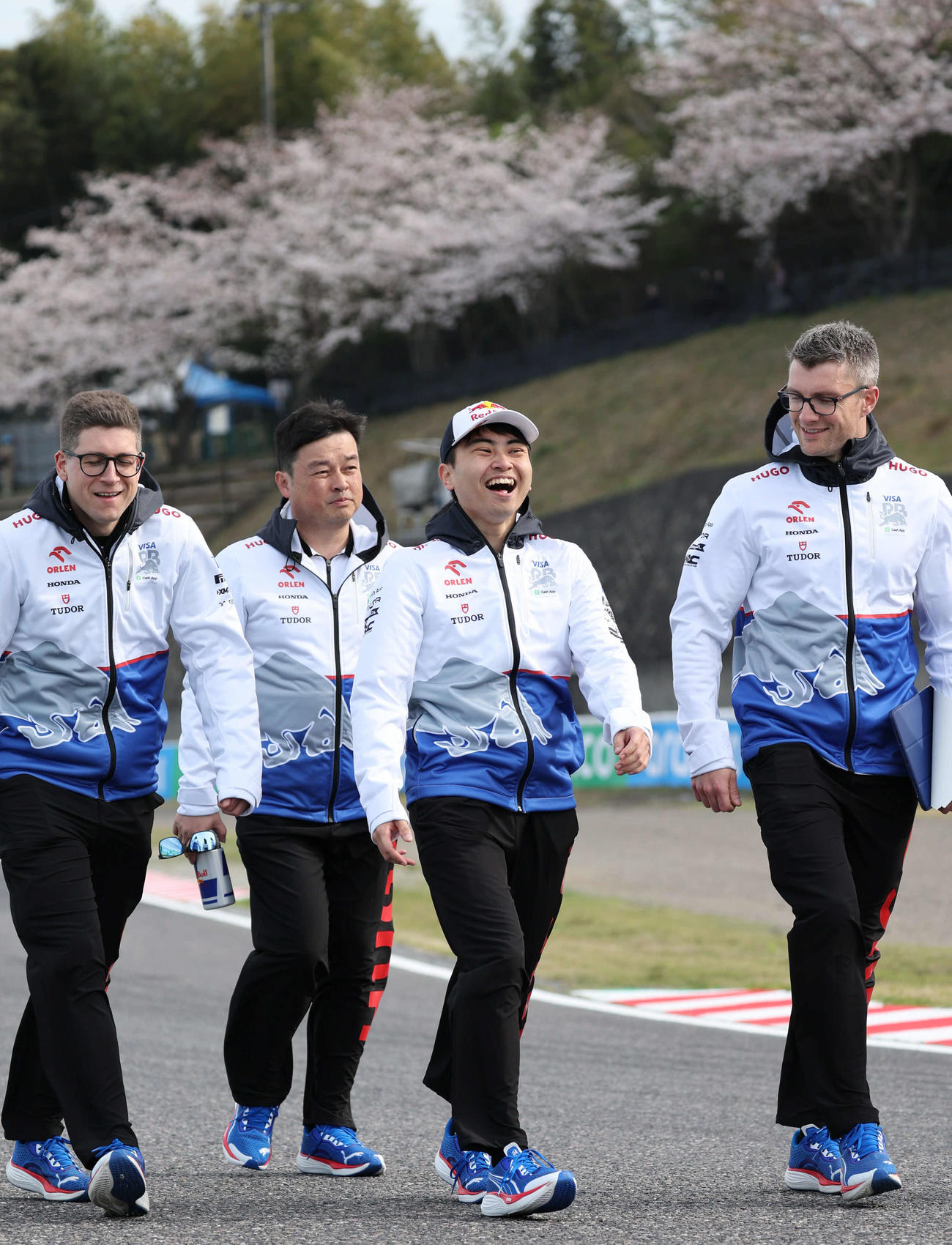 RBでのFP1出走に向け、歩いてコースチェックに出た岩佐歩夢は、S字コーナーに咲く桜をバックに笑顔を見せる（撮影・宮崎幸一）