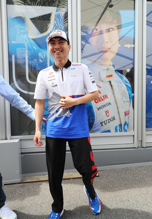 金曜日のFP1出走に向けサーキット入りしたRBの岩佐歩夢は、角田裕毅の写真をバックに笑顔を見せる（撮影・宮崎幸一）