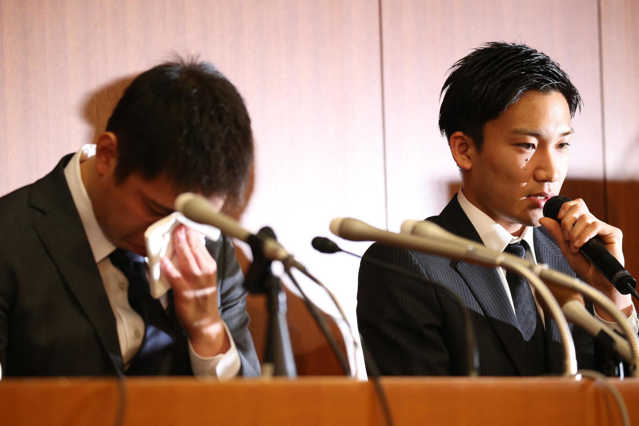 違法カジノ店での賭博行為について会見し、涙を流す田児賢一（左）の横で神妙な表情を見せる桃田賢斗（2016年4月8日撮影）
