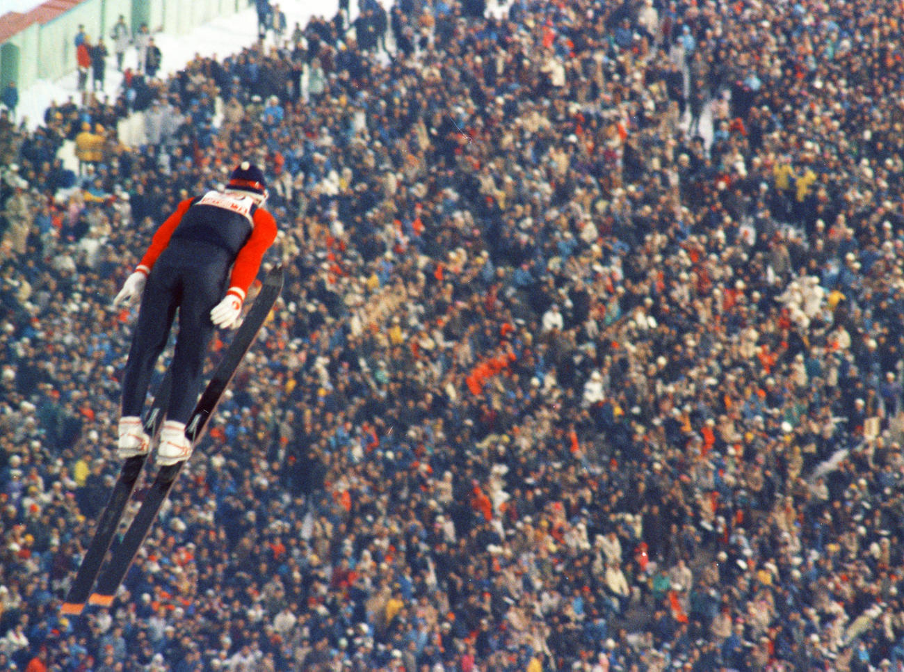 1972年札幌冬季五輪のスキー・ジャンプ90 メートル 級を飛ぶ笠谷幸生さんと満員の観客席＝大倉山（1972年2月11日、共同）