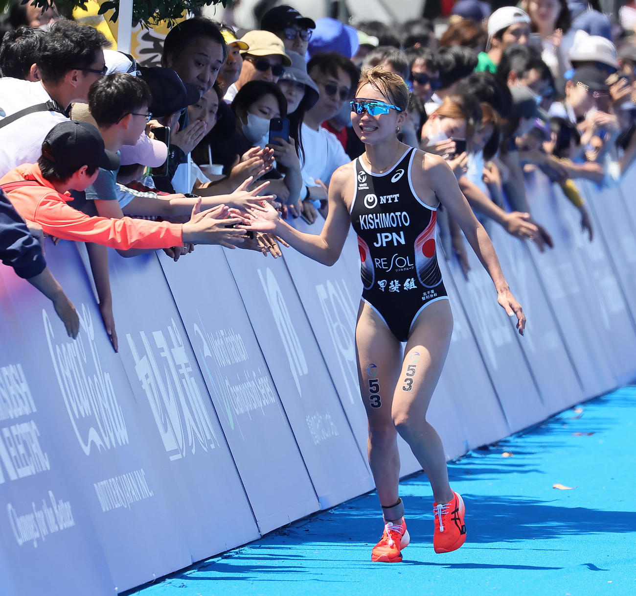 エリート女子競技のランで沿道のファンとタッチを交わしながらゴールへ向かう岸本（撮影・足立雅史）