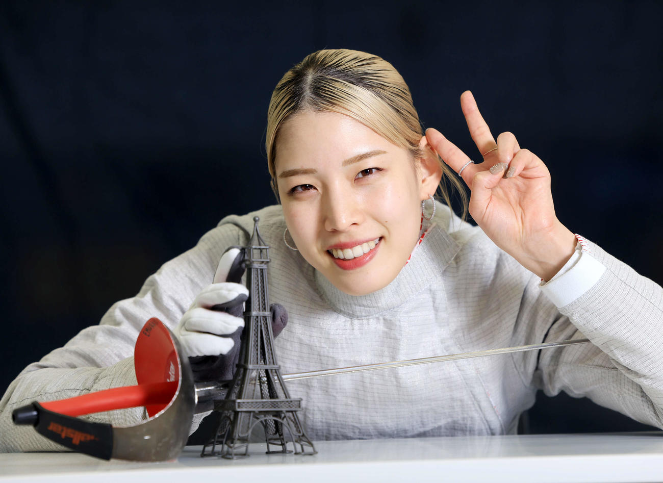 パリ五輪の頂点を目指し、エッフェル塔に手をそえてVサインするフェンシング江村＝本紙正月インタビュー