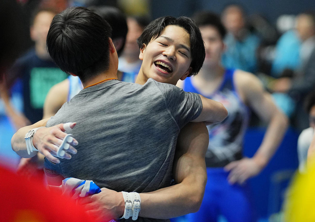鉄棒の演技を終え優勝を決めた岡は同組の選手たちと笑顔で抱き合う（撮影・垰建太）