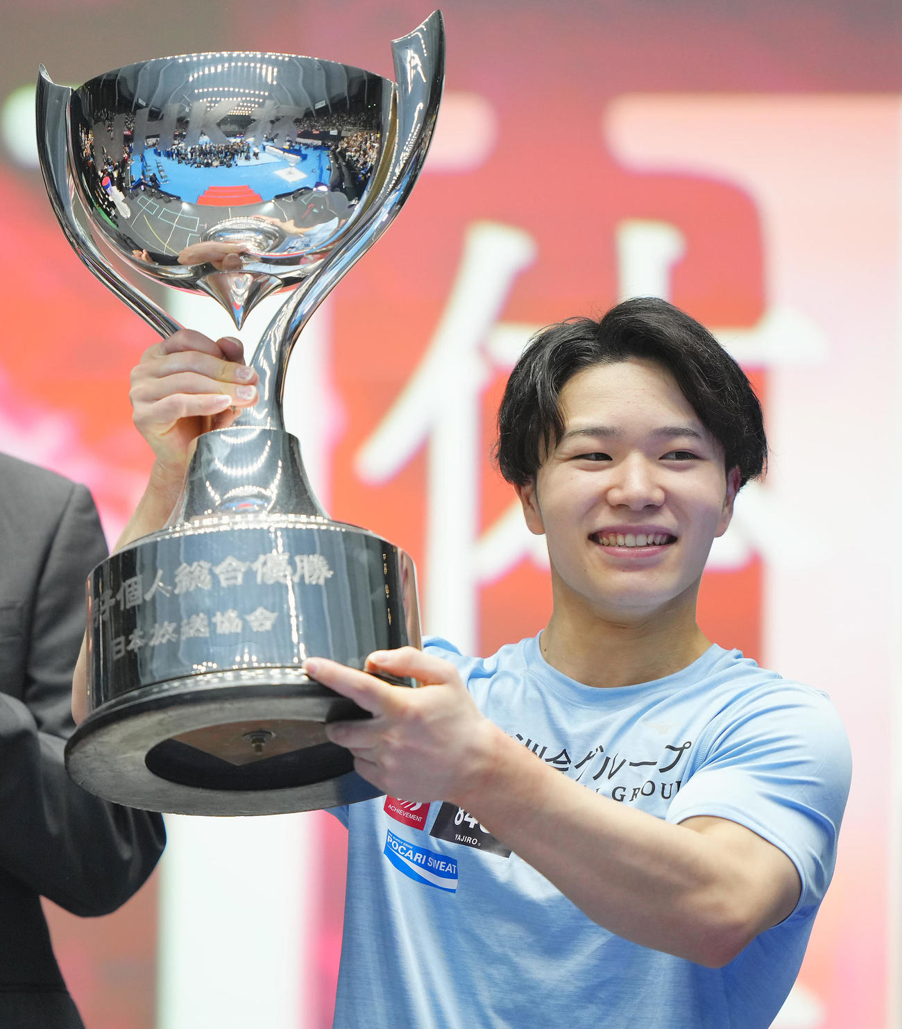 男子個人総合2日目、鉄棒の演技を終え優勝を決めた岡はトロフィーを手に笑顔を見せる（撮影・垰建太）