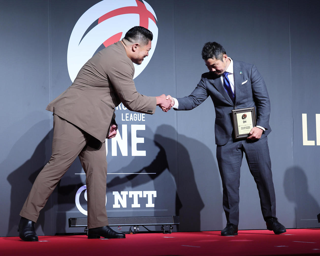 功労賞を受賞した神戸山下（左）と東葛田中は壇上で握手を交わす（撮影・足立雅史）