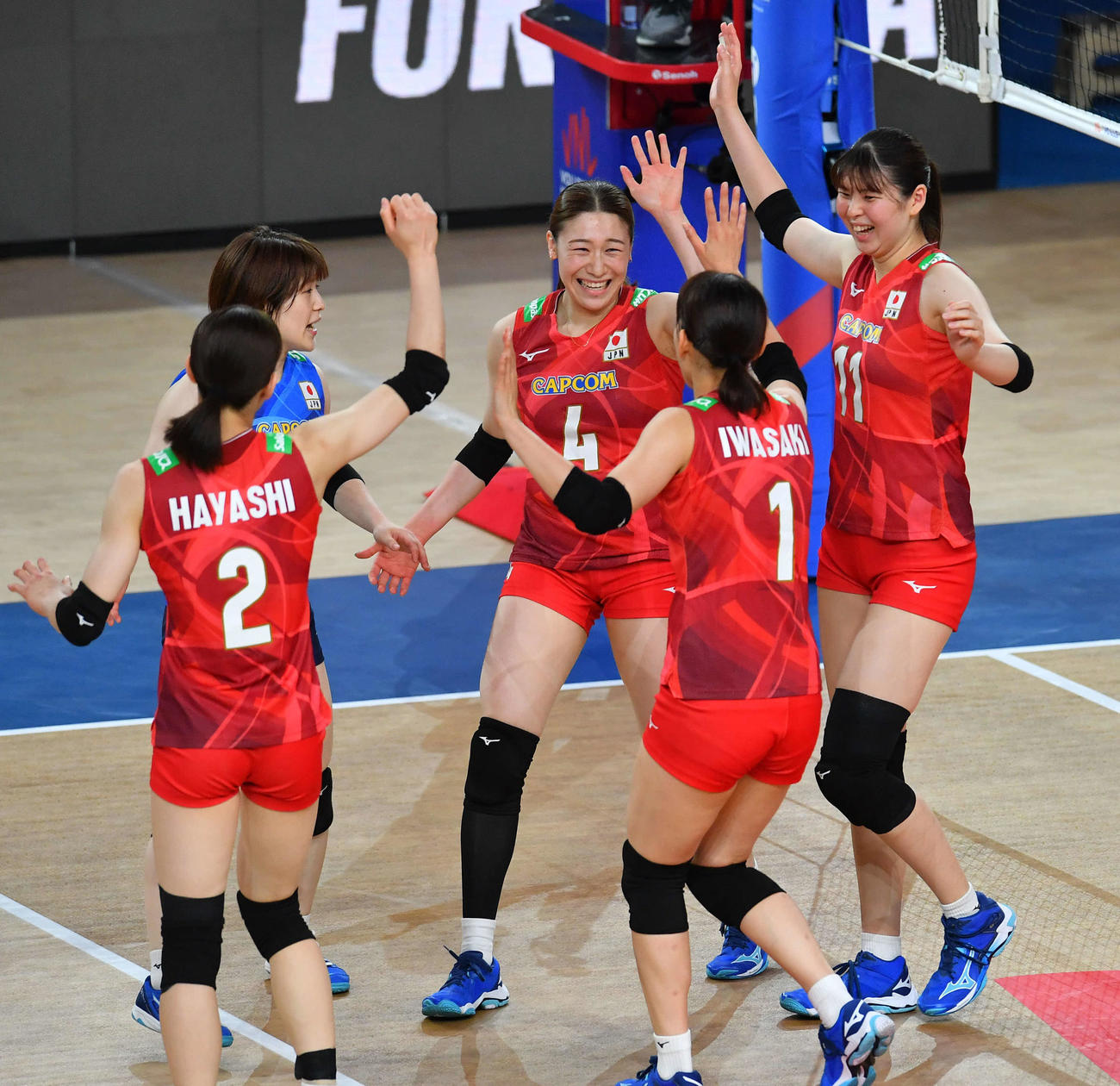 日本対韓国　第1セット、得点を奪い、笑顔でタッチを交わす石川（中央）＝2024年6月12日、西日本総合展示場