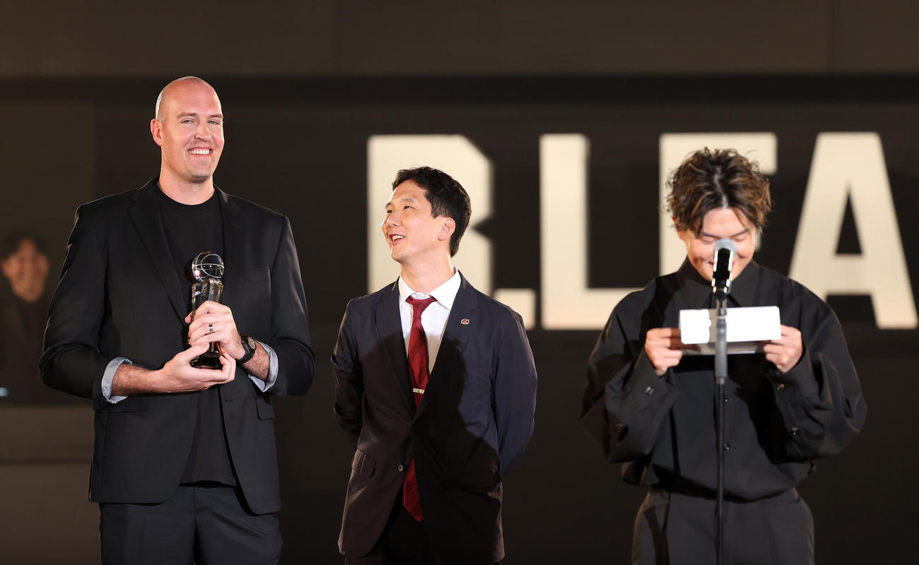 バスケットボール男子Bリーグの年間表彰式「Bリーグアワードショー」　プレゼンターの群馬辻直人（右）が手紙を読み、笑顔を見せる川崎ニック・ファジーカス＝2024年5月31日