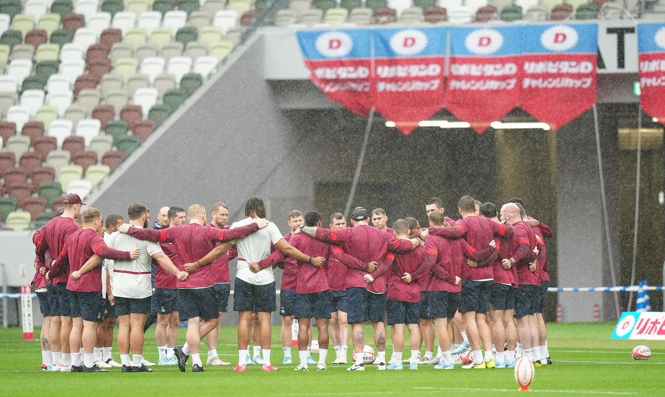 雨の中、ピッチ上の色々な場所で円陣を組み話し合うイングランドの選手たち（撮影・垰建太）