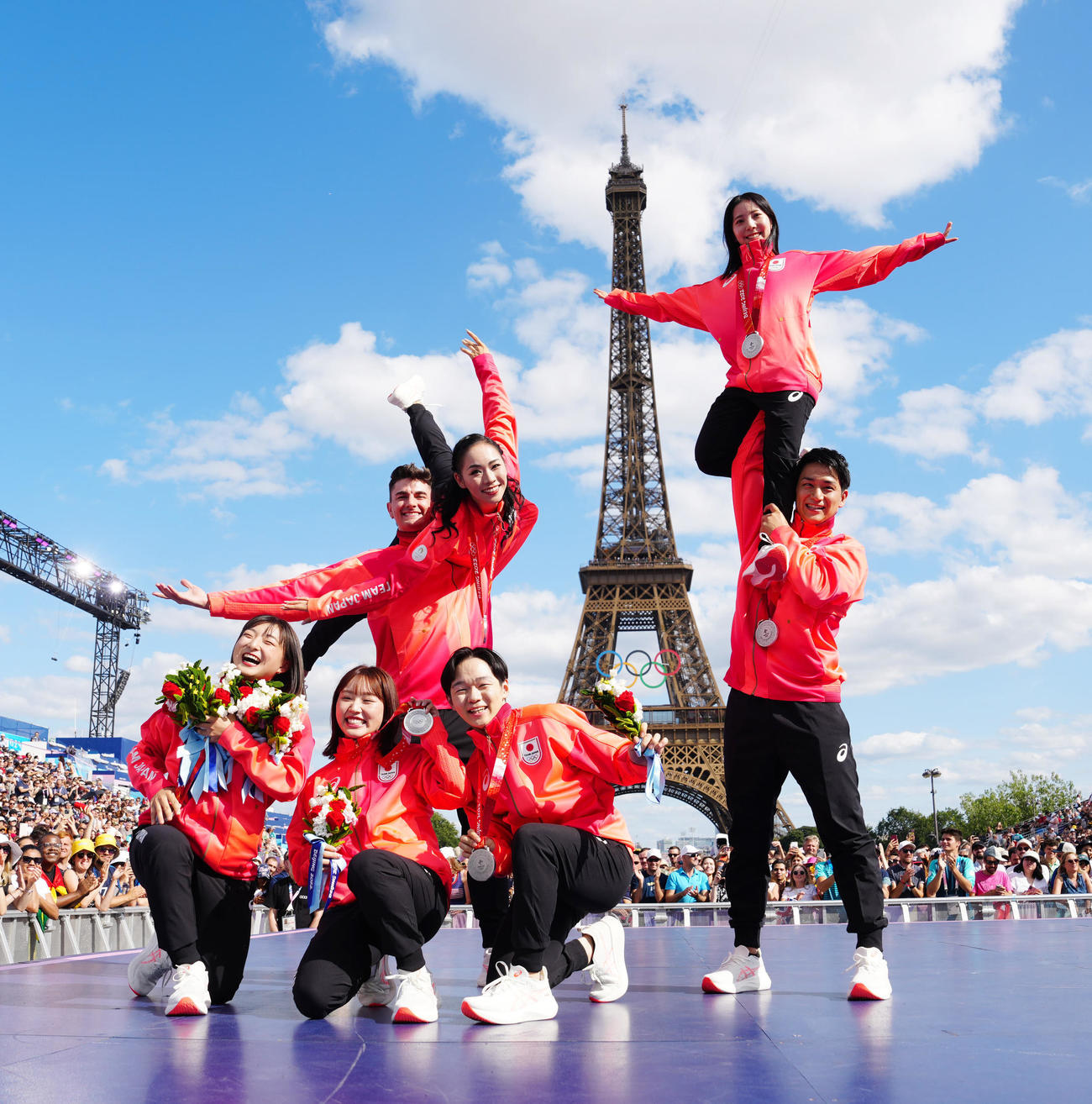 フランス・パリで北京五輪フィギュアスケート団体のメダル授与式に臨み、エッフェル塔を背に写真に納まる日本の選手たち。手前左から坂本花織、樋口新葉、鍵山優真、後方左から小松原尊、小松原美里、三浦璃来、木原龍一（撮影・江口和貴）