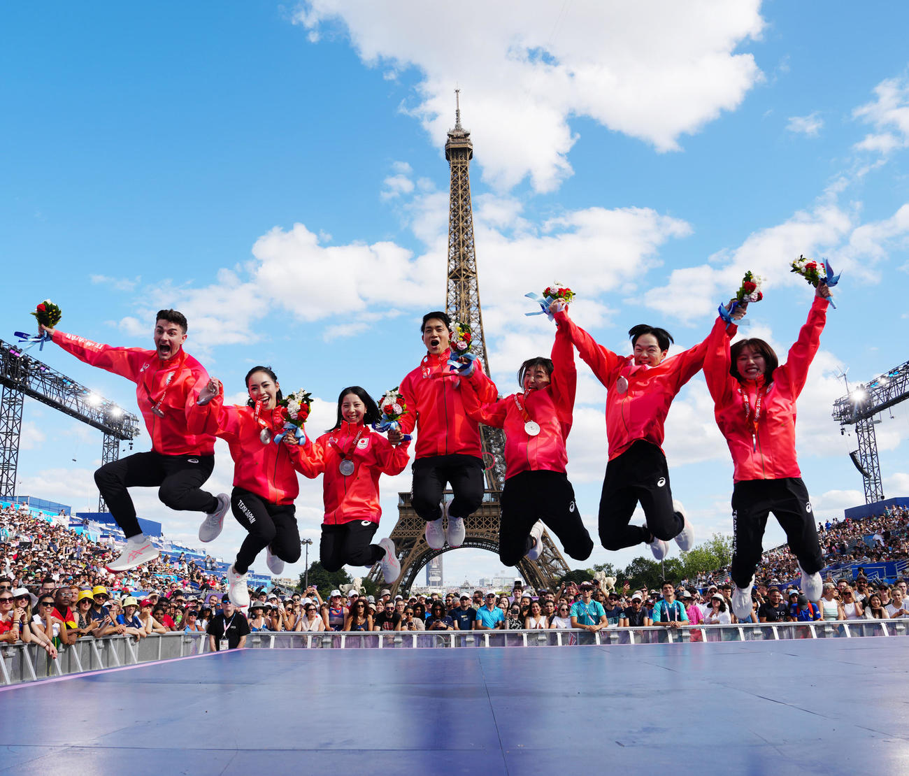 フランス・パリで北京五輪フィギュアスケート団体のメダル授与式に臨み、エッフェル塔を背に写真に納まる日本の選手たち。左から小松原尊、小松原美里、三浦璃来、木原龍一、坂本花織、鍵山優真、樋口新葉（撮影・江口和貴）