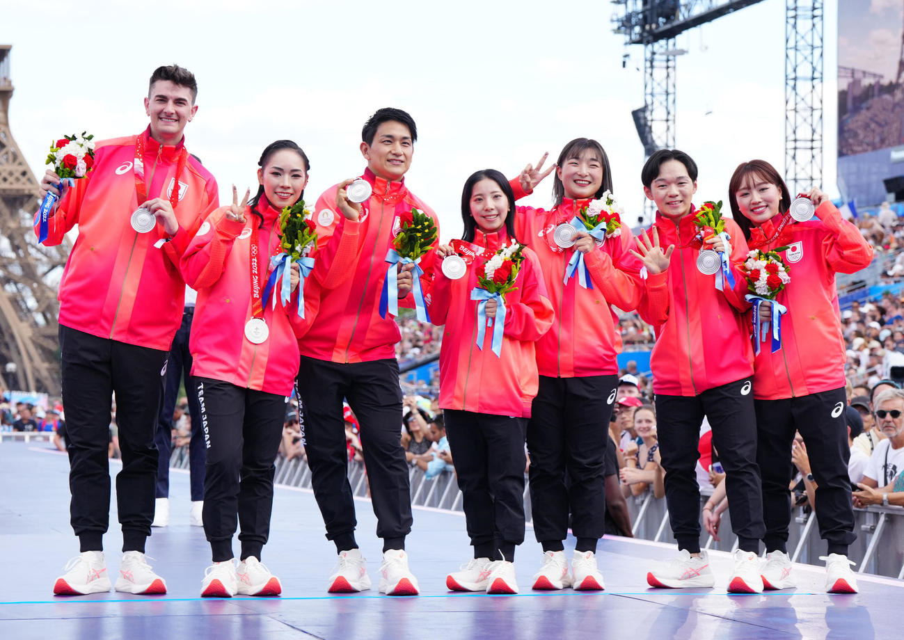 フランス・パリで北京五輪フィギュアスケート団体のメダル授与式に臨み、エッフェル塔を背に写真に納まる日本の選手たち。左から小松原尊、小松原美里、木原龍一、三浦璃来、坂本花織、鍵山優真、樋口新葉（撮影・江口和貴）