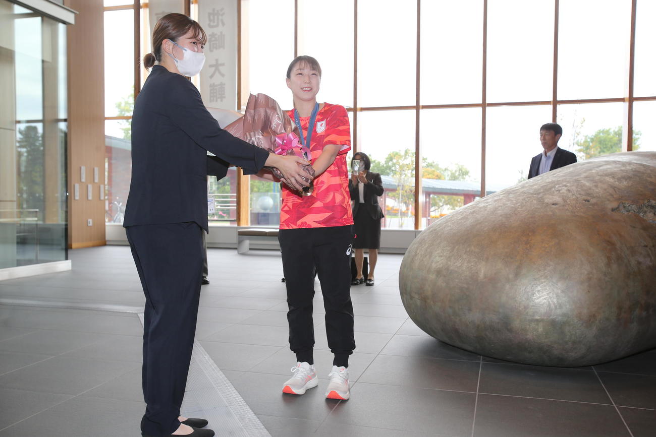 故郷・北海道の岩見沢市役所を表敬訪問したパリ五輪バドミントン女子混合ダブルス銅メダリストの五十嵐（右）は、花束を受け取り笑顔（撮影・中島洋尚）