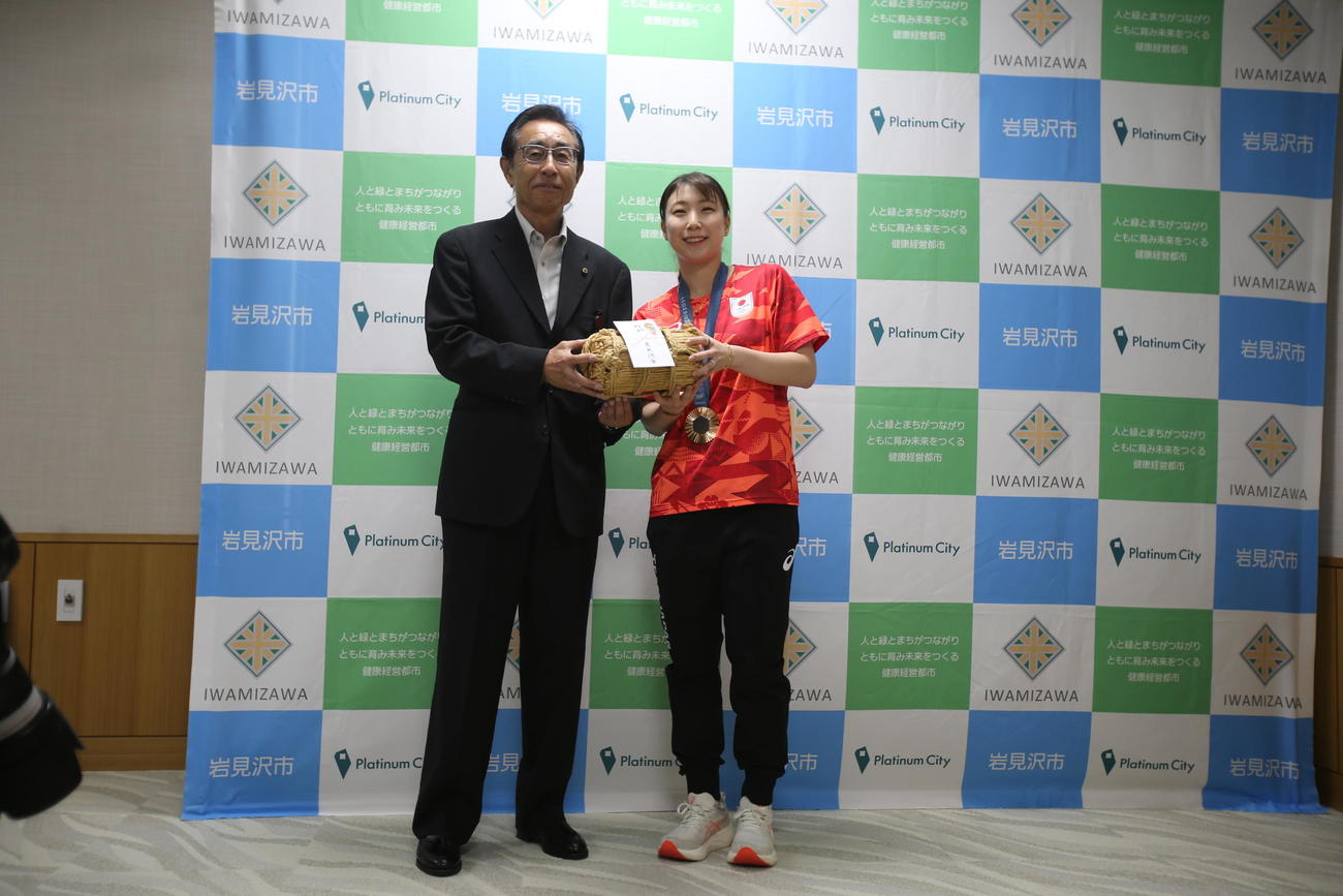 故郷・北海道の岩見沢市役所を表敬訪問したパリ五輪バドミントン女子混合ダブルス銅メダリストの五十嵐（右）は60キロの新米を受け取り笑顔（撮影・中島洋尚）