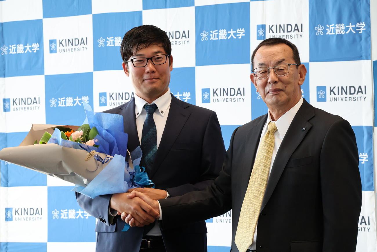 花束を持つ古川高晴（左）と、近大洋弓部の山田秀明監督（撮影・竹本穂乃加）＝2024年10月21日、大阪・東大阪市内