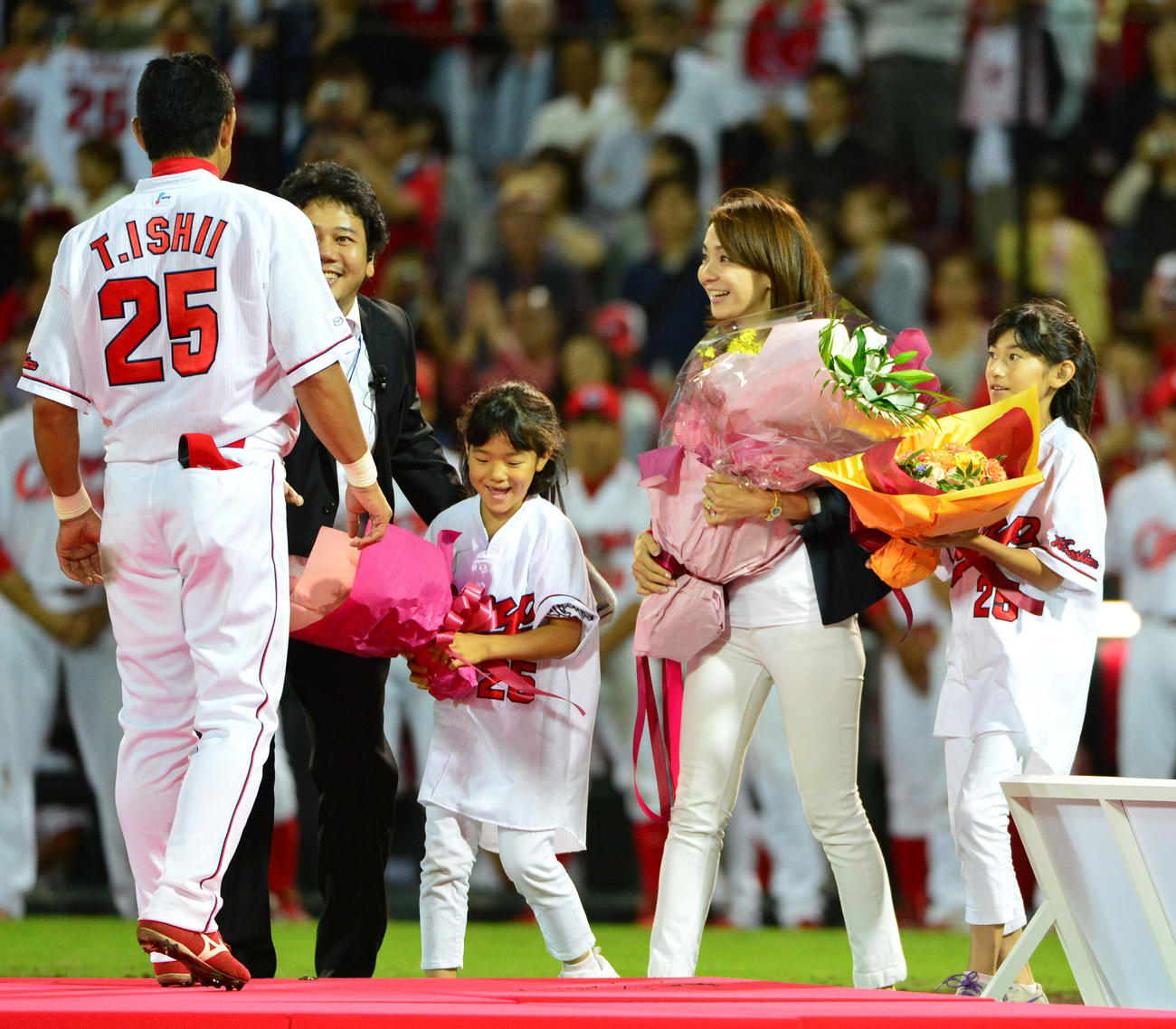 広島対阪神24回戦　試合後の引退セレモニーで詩織夫人（右から2人目）、娘のはる佳ちゃん（右）、さやかちゃん（左から3人目）から花束を受け取る石井琢朗（2012年9月30日撮影）