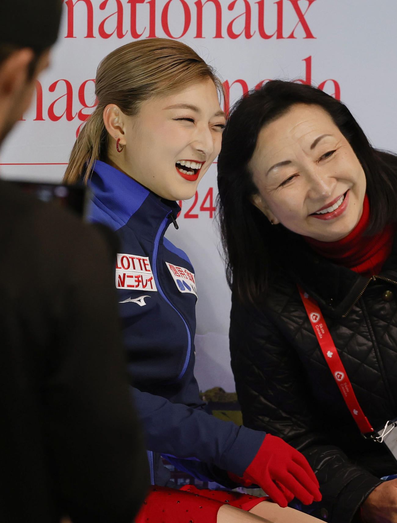 女子SPの演技を終え、キスアンドクライで笑顔を見せる坂本花織（左）（共同）