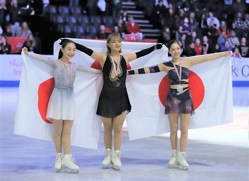 フィギュアスケートGPシリーズスケートカナダ 表彰式で日の丸を掲げる、左から松生理乃、坂本花織、吉田陽菜(撮影・藤塚大輔)