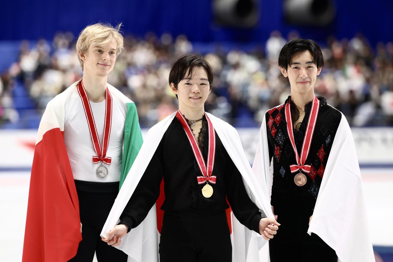 表彰式後、笑顔で記念撮影に臨む男子優勝の鍵山（中央）。左は2位のダニエル・グラスル、右は3位の壷井（撮影・河田真司）