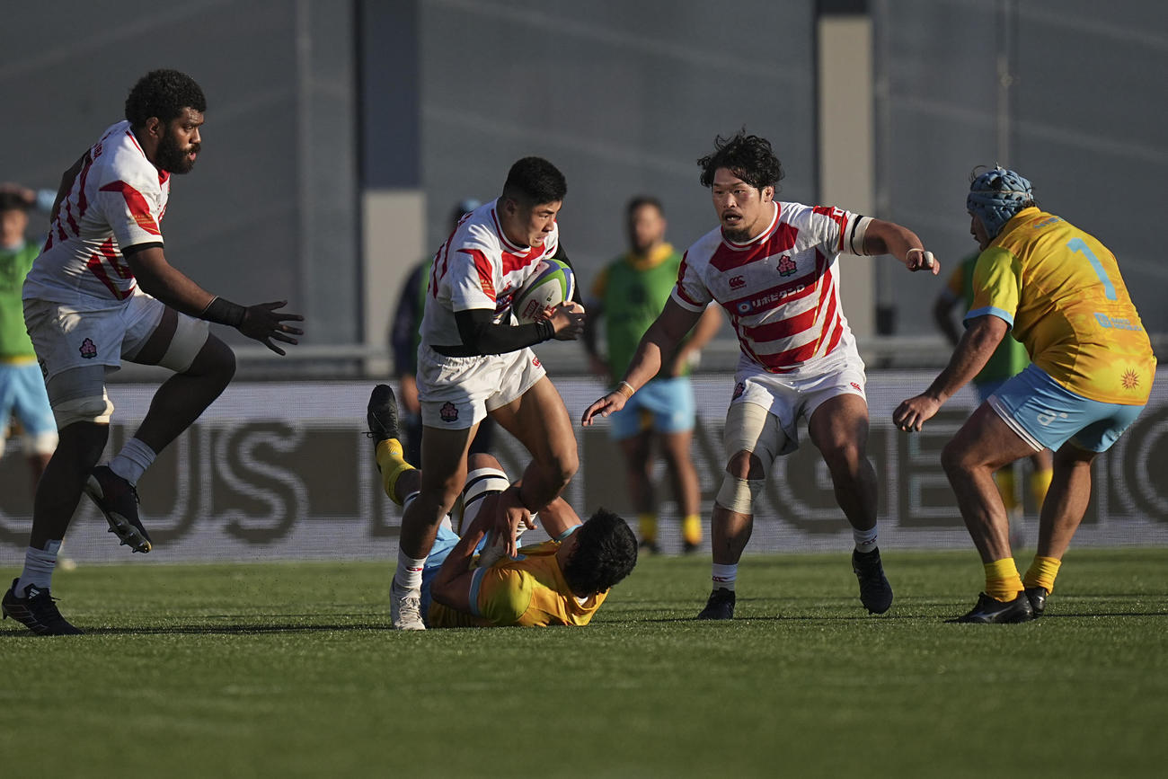 タックルを受けながら前進する濱野隼大（AP)