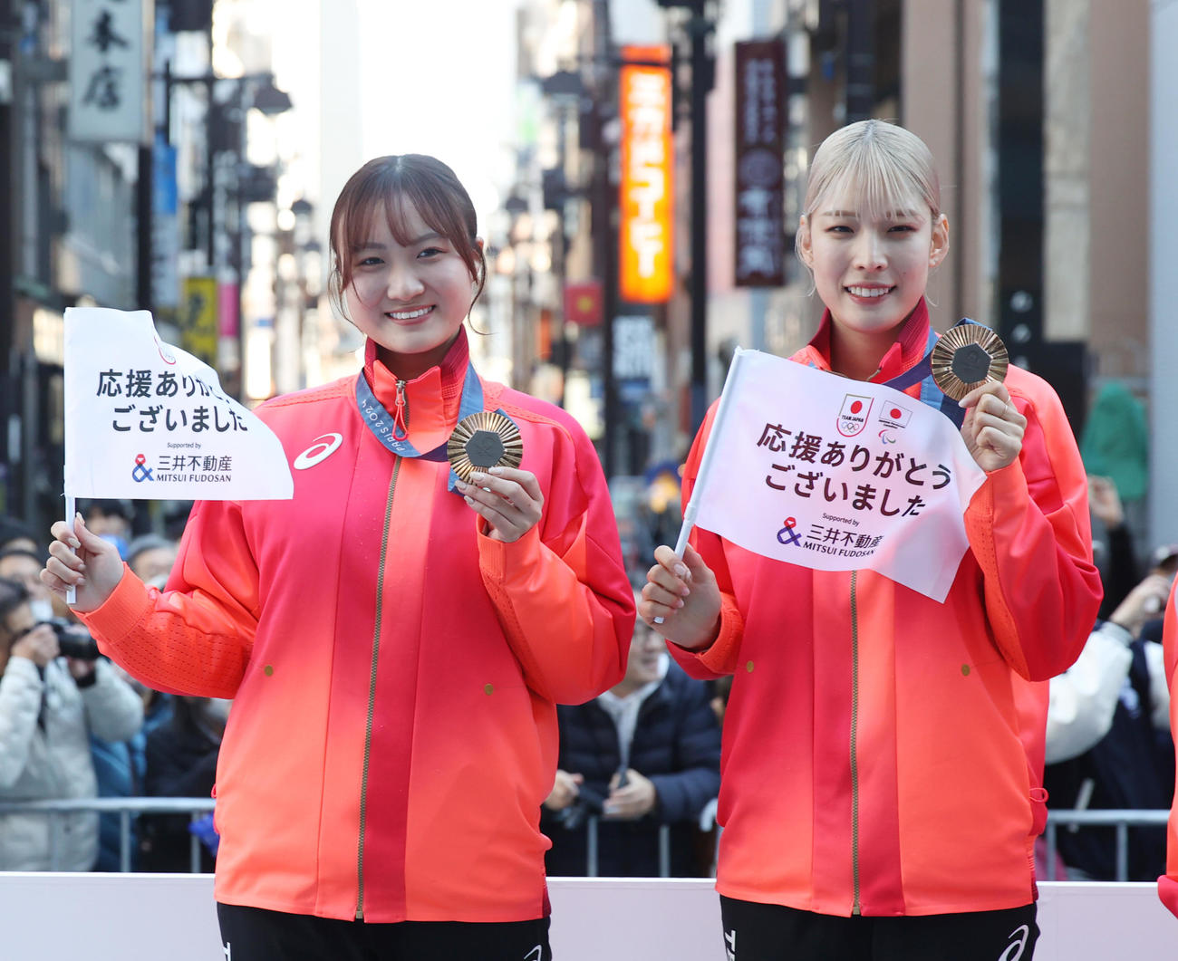 パリ五輪・パラのパレードで撮影に応じるフェンシング女子サーブル団体銅メダルの尾崎（左）と江村（撮影・柴田隆二）