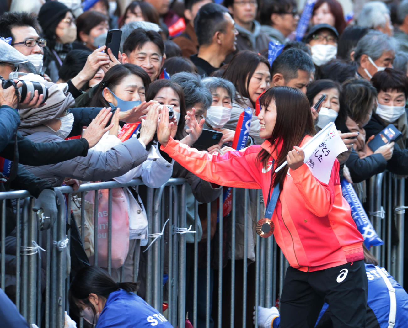 パリ五輪・パラのパレードでハイタッチする女子フリースタイル50キロ級銅メダルの須崎（撮影・柴田隆二）
