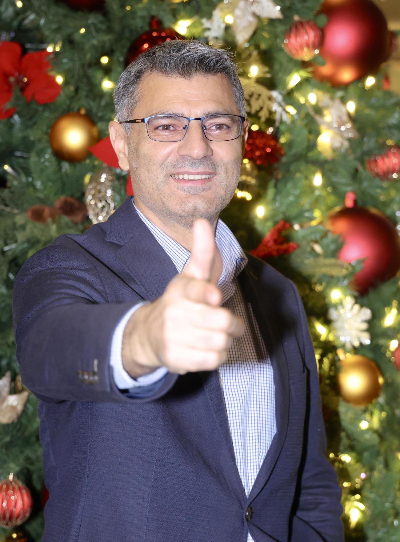 クリスマスツリーを背に、ポーズを決め写真に納まるパリ五輪射撃銀メダリストの、「無課金おじさん」ことユスフ・ディケチ（撮影・河田真司）