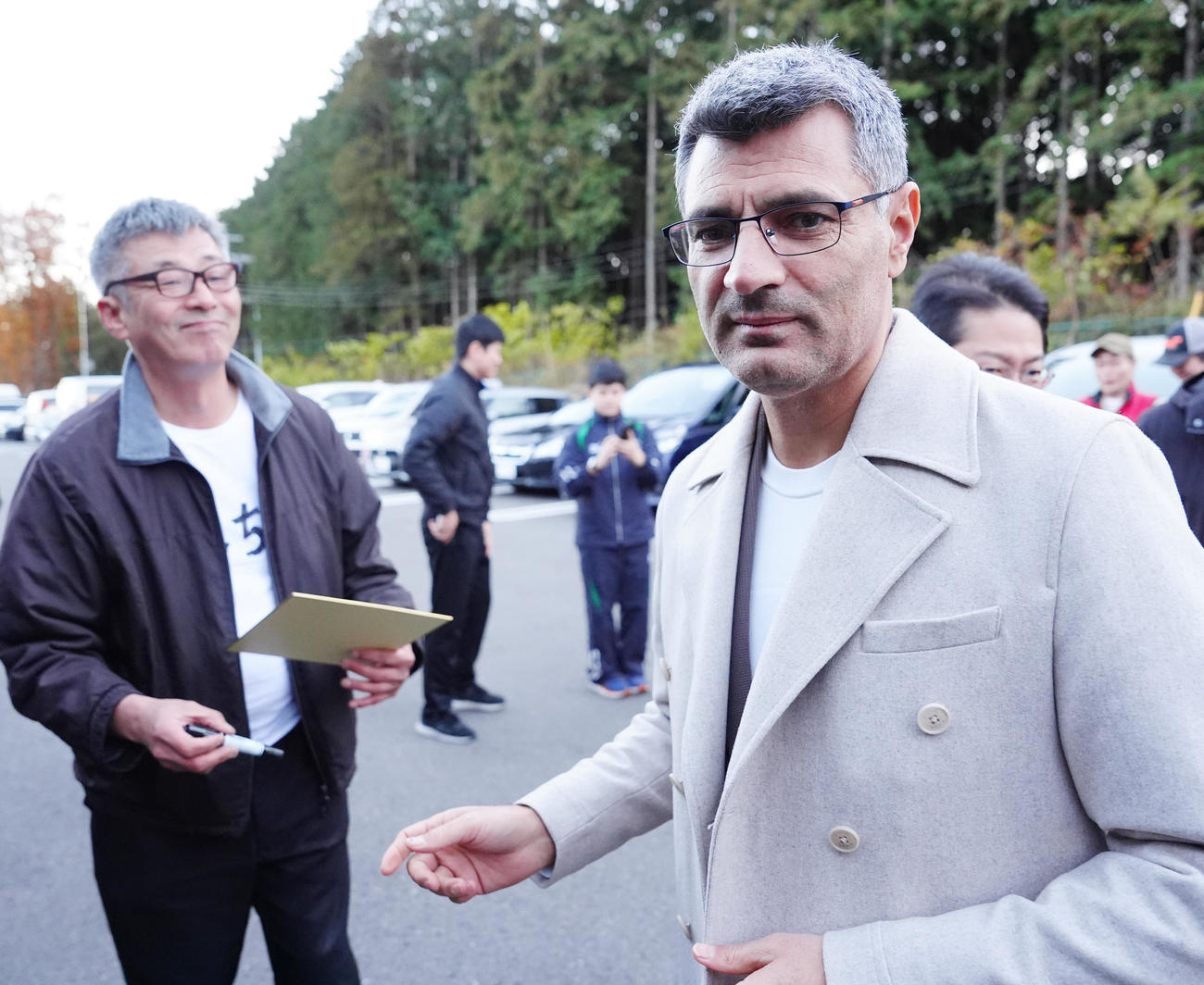 栃木県ライフル射撃場に到着し、待ち構えたファンのそっくりさんへサインした「無課金おじさん」ことディケチ（右）（撮影・江口和貴）