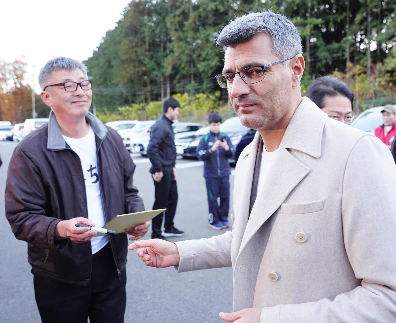 栃木県ライフル射撃場に到着し、待ち構えたファンのそっくりさんへサインした「無課金おじさん」ことディケチ（右）（撮影・江口和貴）