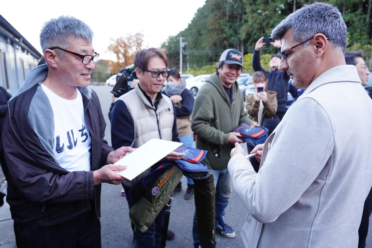 栃木県ライフル射撃場に到着し、待ち構えたファンへのサインに応じる「無課金おじさん」ことユスフ・ディケチ（右）（撮影・江口和貴）