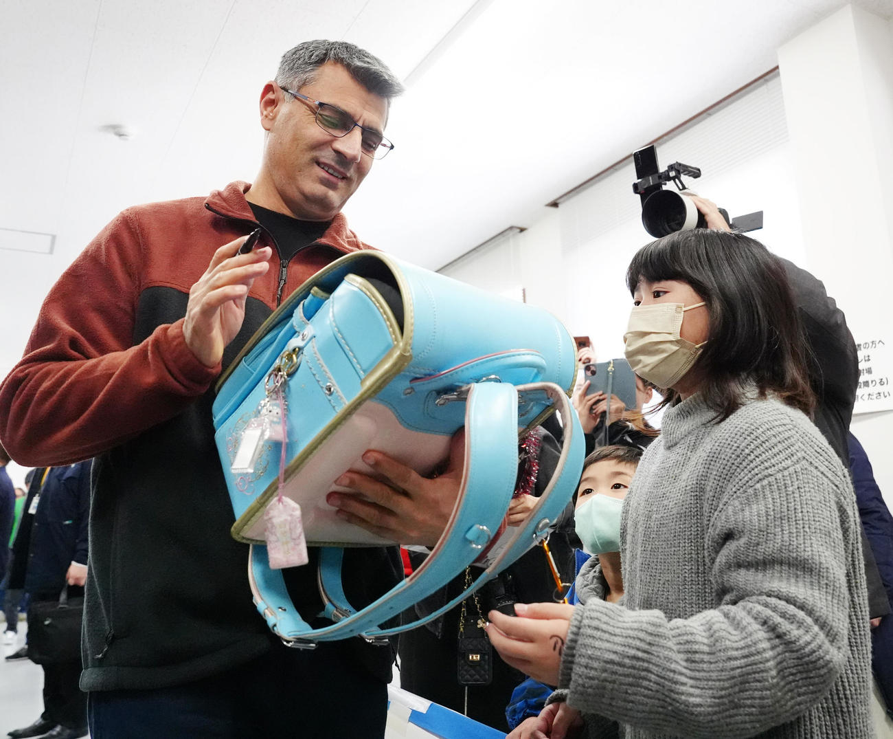 小学3年生の女の子のランドセルにサインする「無課金おじさん」ことディケチ（左）（撮影・江口和貴）