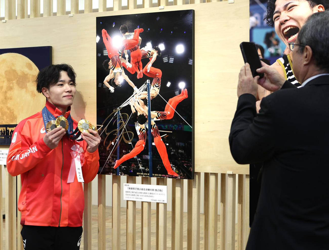 日本橋三越で開幕した「2024報道写真展」で自身のパネルの前で記念撮影する岡（撮影・水谷安孝）