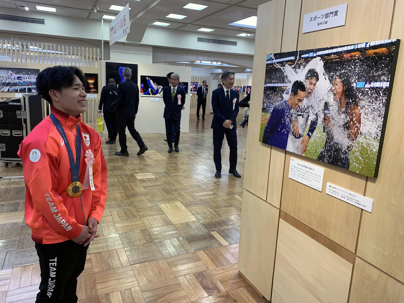 報道写真展でスポーツ部門賞海外を獲得したドジャース大谷のウォーターシャワーの写真を笑顔で鑑賞する体操の岡（撮影・宇治久裕）