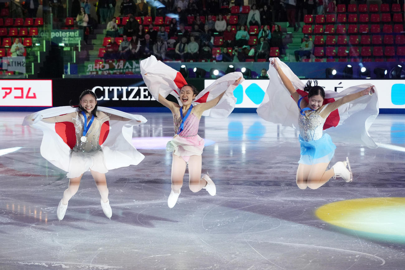 グランプリファイナルのジュニア女子フリーを終え表彰台を独占し日の丸を背にジャンプする、左から2位の和田、優勝した島田、3位の中井（2024年12月6日撮影）