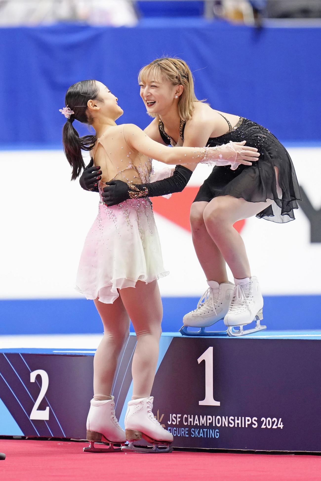 女子の表彰式で2位の島田麻央（左）と抱き合う坂本花織（共同）