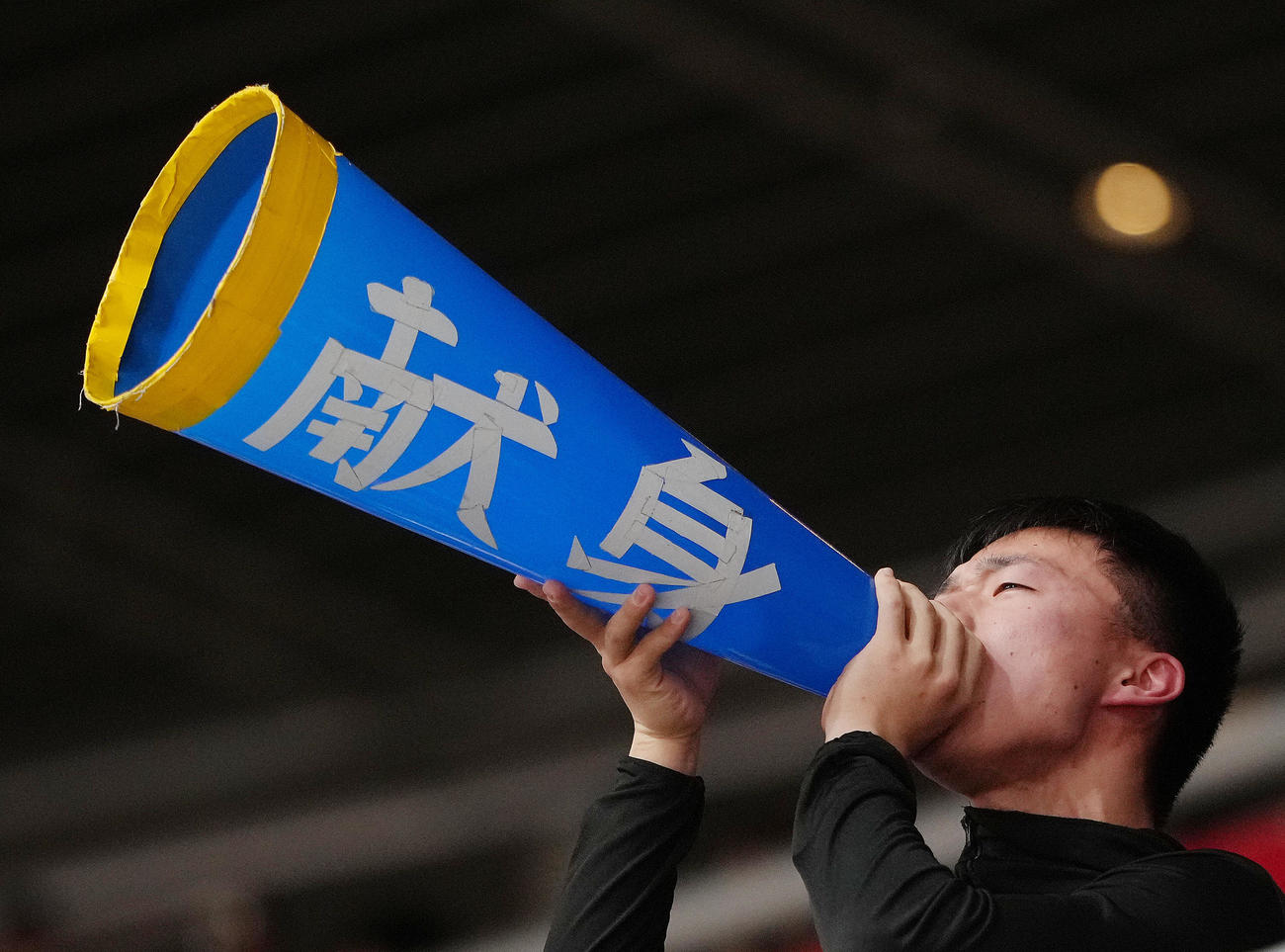 新田対藤枝明誠　「献身」のテープが貼られたメガホンで声援を送る藤枝明誠（撮影・足立雅史）